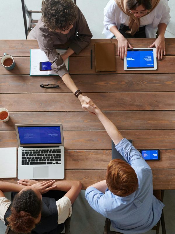 Overhead view of colleagues in a work meeting using laptops and tablets, emphasizing teamwork and technology.